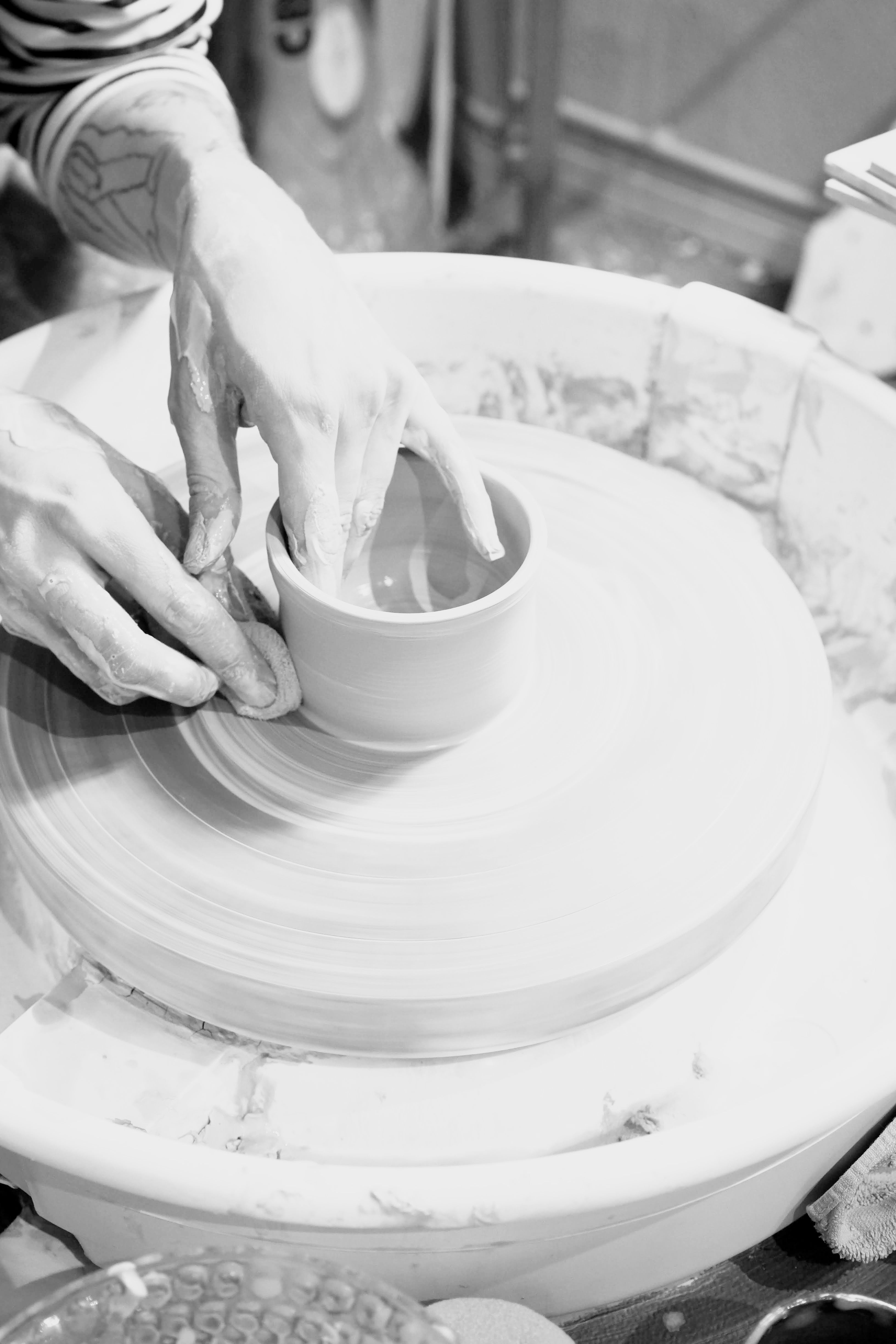 Person working with clay on a pottery wheel in a studio setting