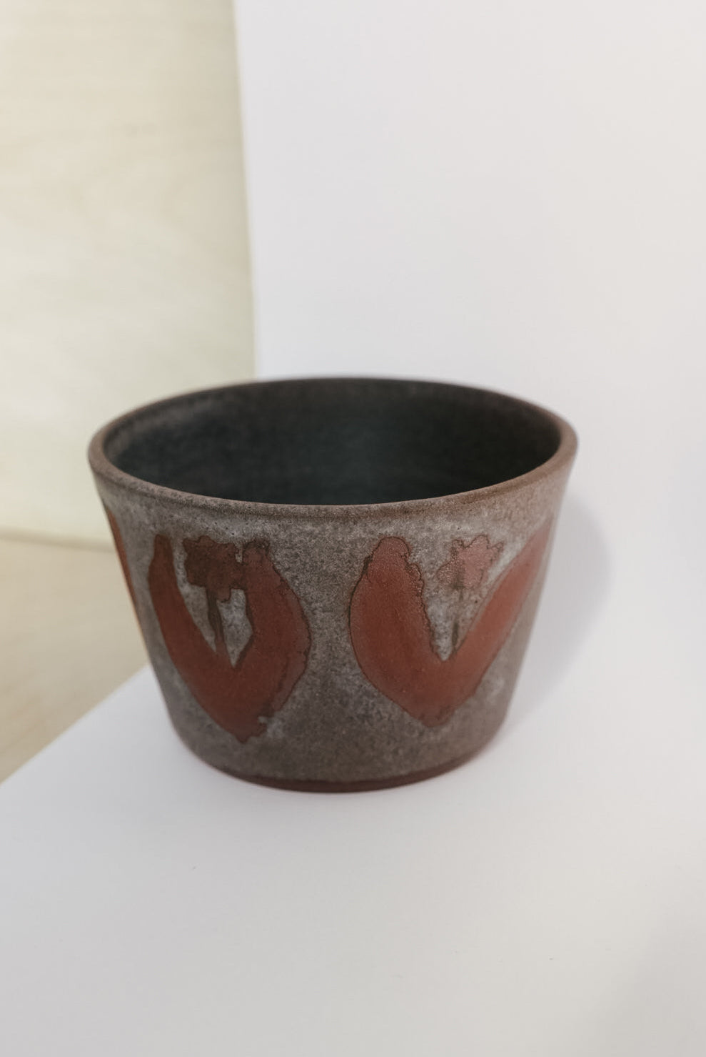 Ceramic cup with red patterns on a white surface