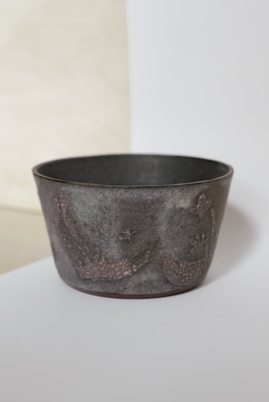 Dark ceramic pot on a light surface with a neutral background