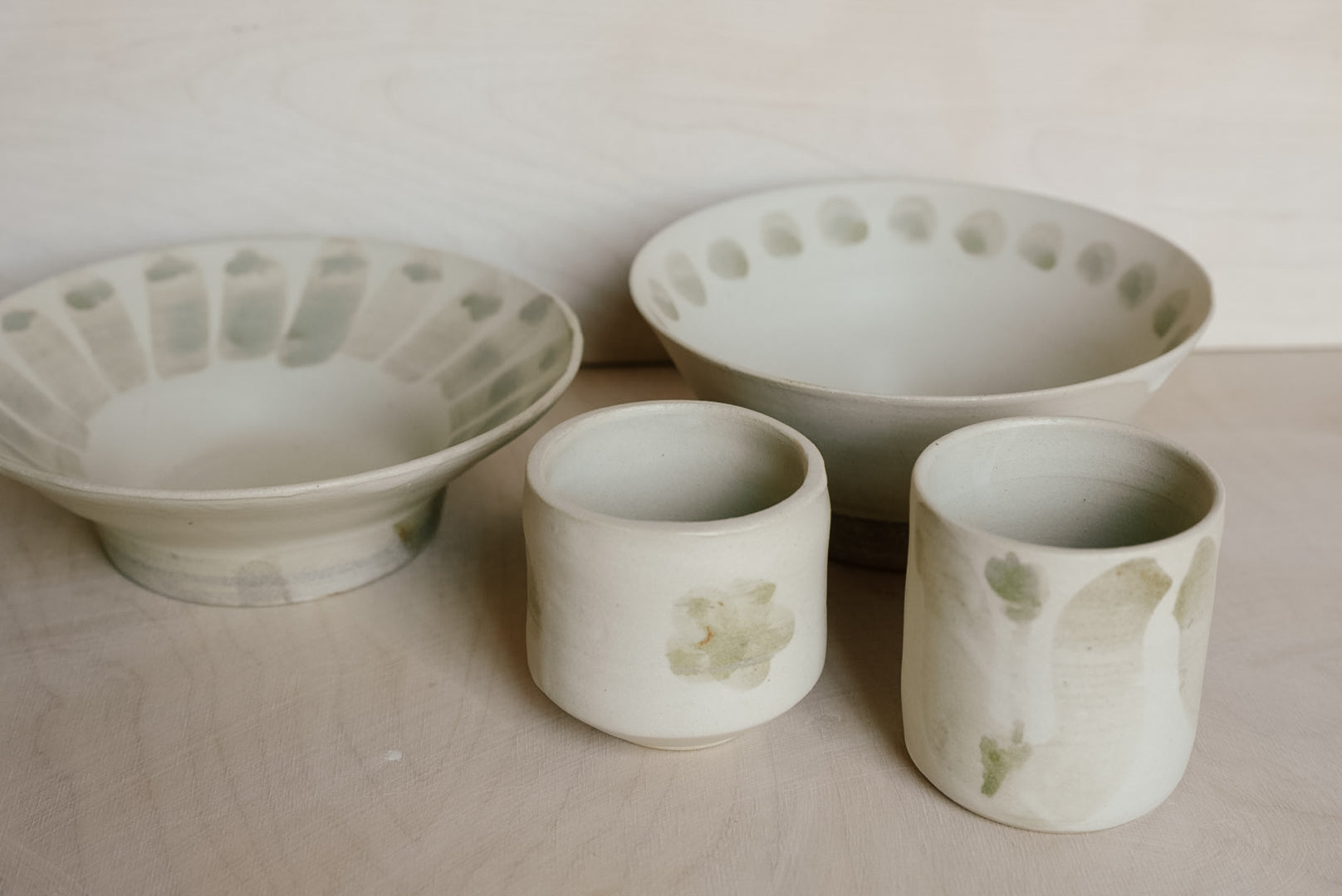 Set of ceramic bowls and cups with textured surfaces on a neutral background