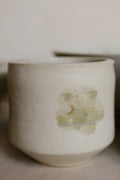 Ceramic cup with a green leaf design on a neutral background