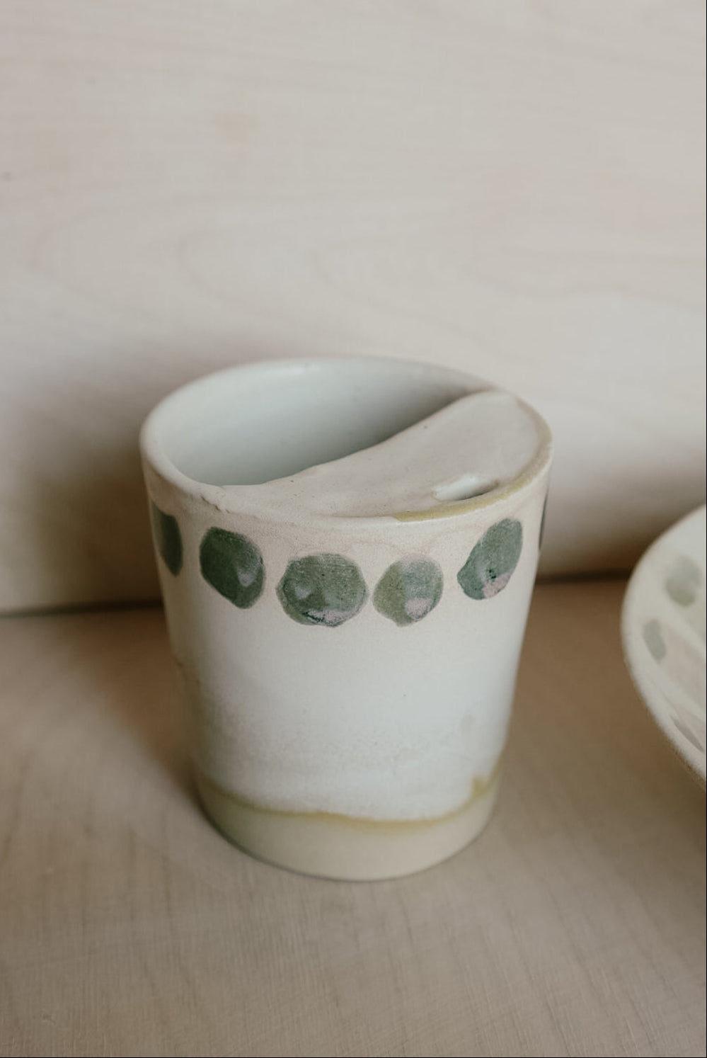 Ceramic cup with green polka dots on a wooden surface
