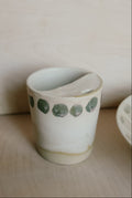 Ceramic cup with green polka dots on a wooden surface