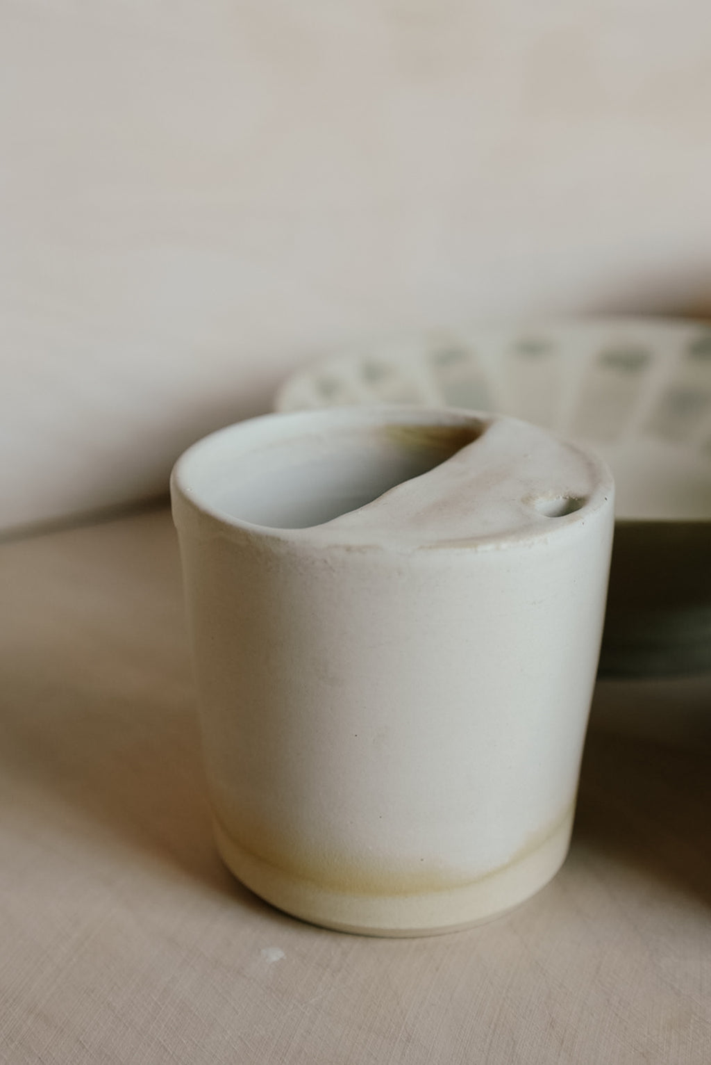 White ceramic cup on a beige surface with a blurred background
