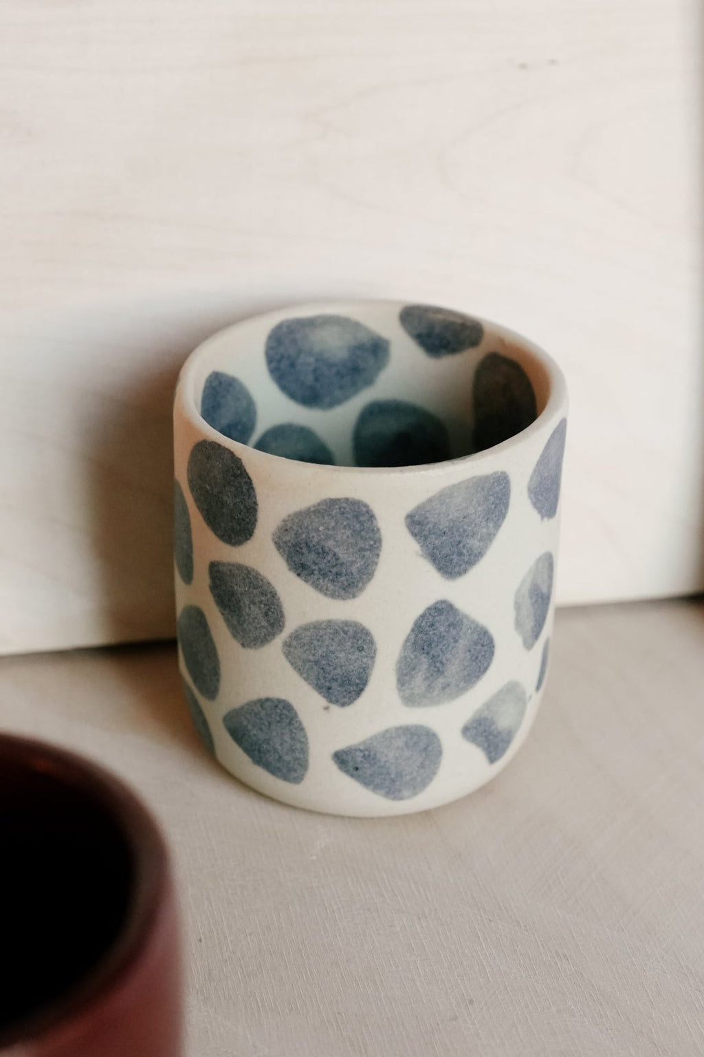 Ceramic cup with blue dot pattern on a plain background