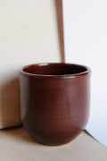 dark red ceramic cup on a neutral background
