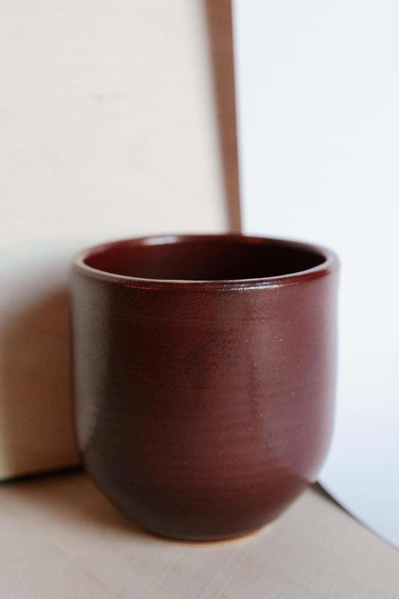 dark red ceramic cup on a neutral background