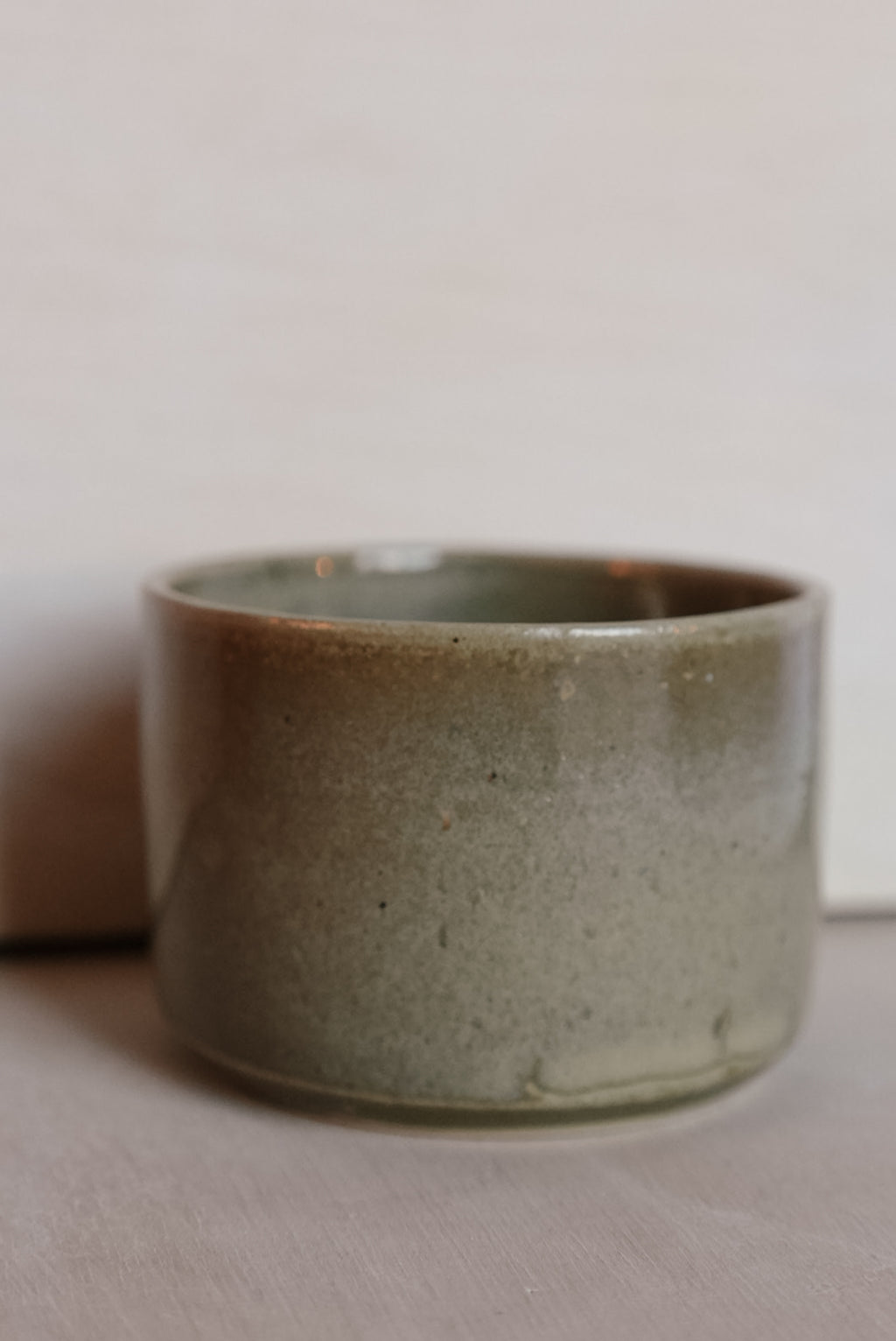 Green ceramic cup on a light surface with a neutral background