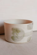 Ceramic cup with green tulip design on a neutral background