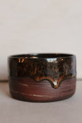 Brown ceramic cup with a textured surface on a light background
