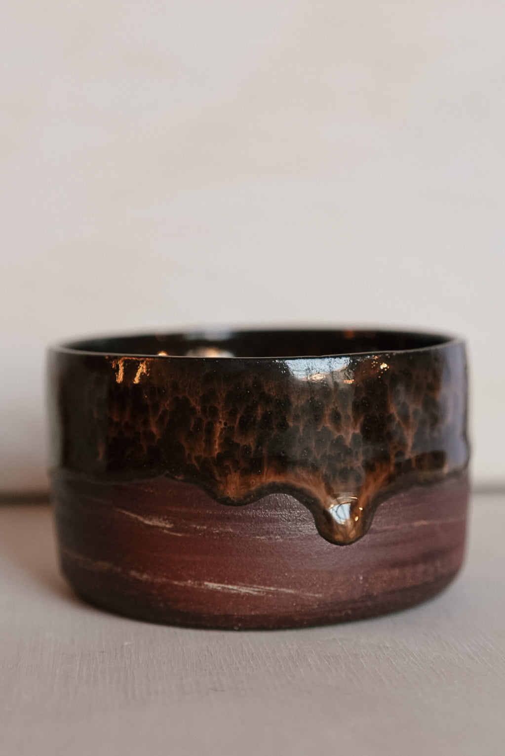 Brown ceramic cup with a textured surface on a light background